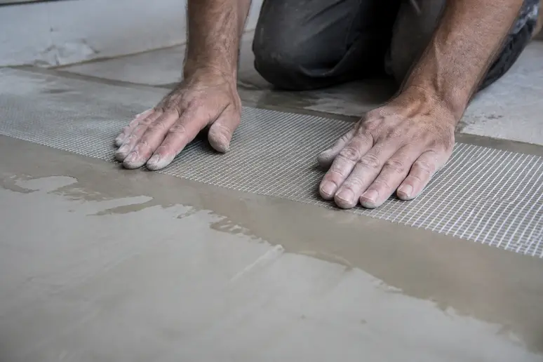 Application d'un treillis de fibre de verre sur le support en préparation pour le béton ciré sur carrelage.