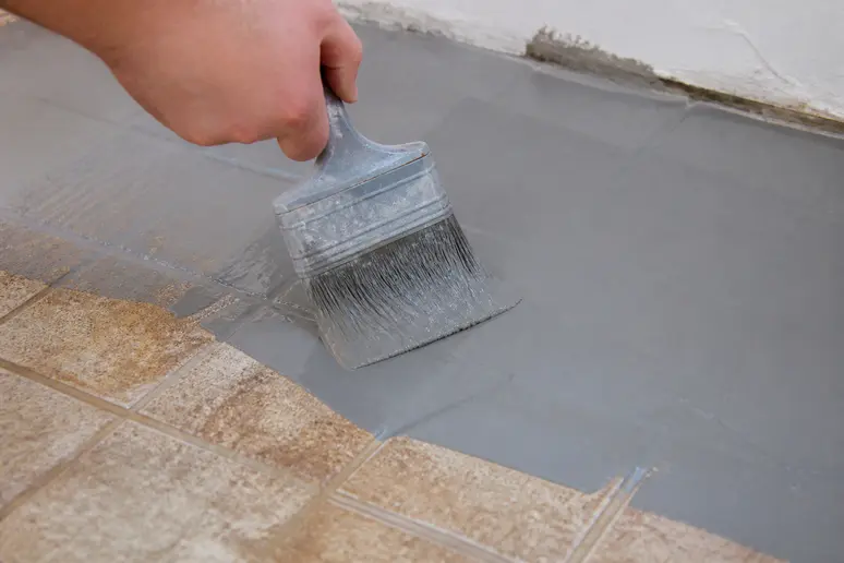 Application d'un primaire d'adhérence sur un ancien carrelage avant pose de colle flex.