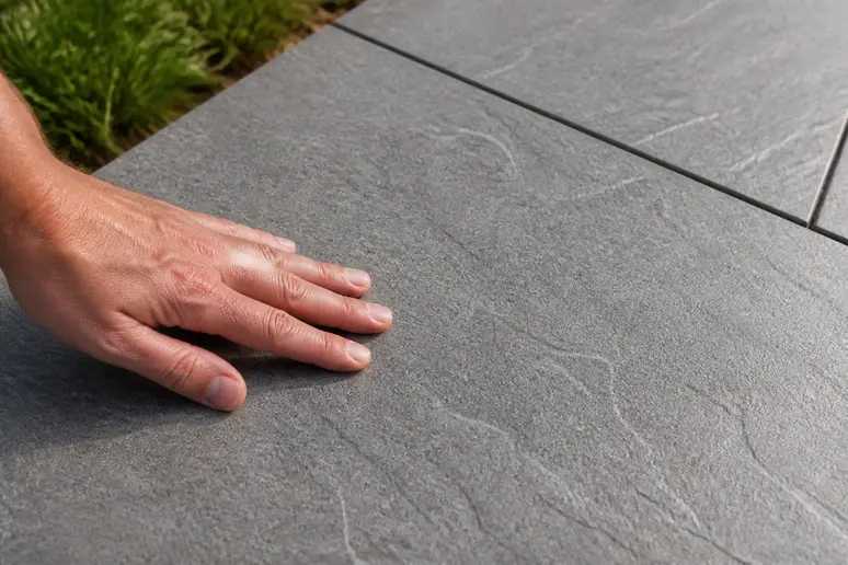 Gros plan sur un carrelage effet pierre texturé gris anthracite pour extérieur, offrant une adhérence sécurisée.
