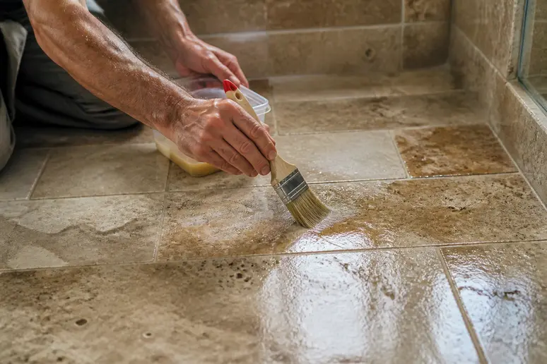 Application d'un traitement hydrofuge sur des dalles de carrelage travertin salle de bain.
