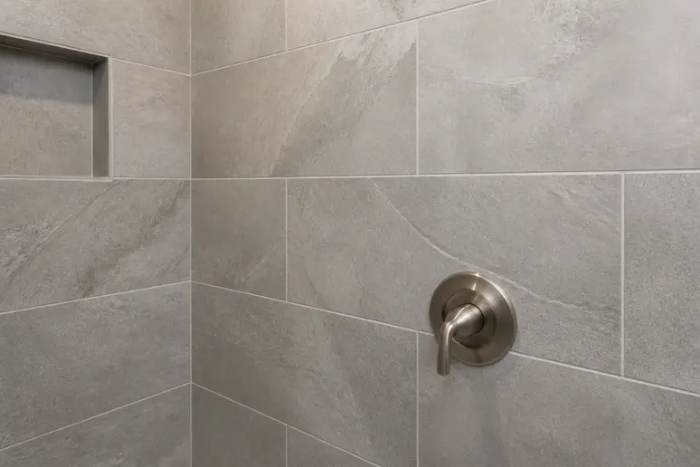 Pose murale de carreaux grand format pour un carrelage travertin salle de bain soigné.