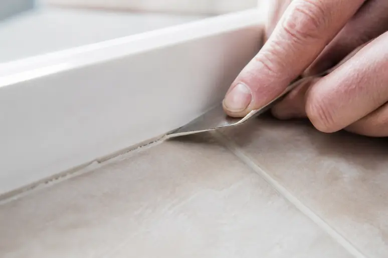 Technique manuelle pour décoller un joint de silicone avec une lame fine sur carrelage, comment enlever du silicone sur du carrelage.