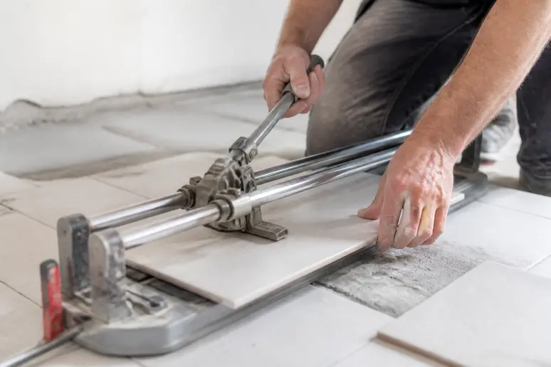 Artisan carreleur effectuant une découpe de précision sur un carreau pour un devis carrelage