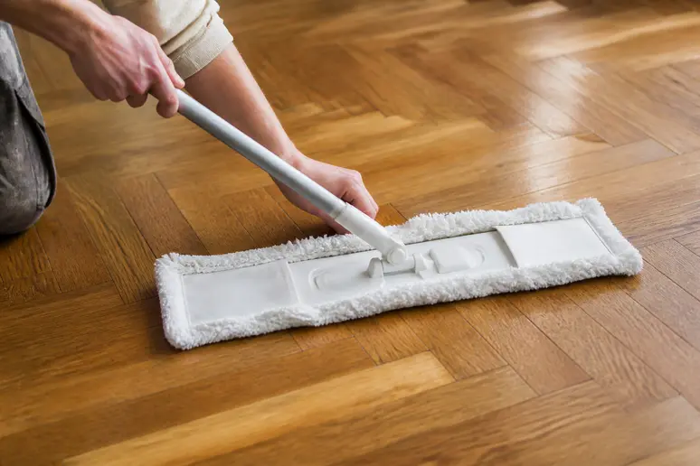 Application d'une huile entretien parquet au balai microfibre sur le sol en bois