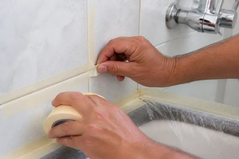 Application de ruban de masquage pour protéger le carrelage avant de nettoyer les joints.