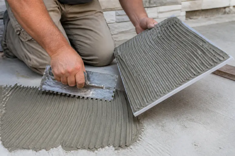 Application de la colle sur la dalle et le carreau pour une pose carrelage exterieur sans vide d'air