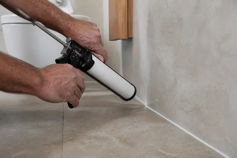 Gestion des joints pour réussir la pose du carrelage : application de mastic autour d'une pièce d'eau.