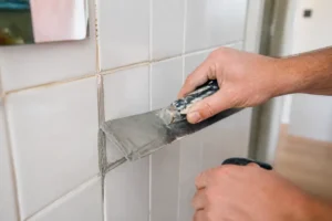 Application d'un nouveau mortier pour refaire joint carrelage sur joint existant dans une salle de bain.