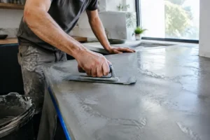 artisan appliquant soigneusement du béton ciré sur un plan de travail de cuisine moderne