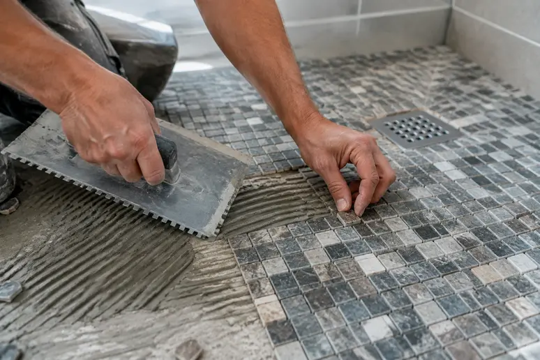 Pose de mosaïque sur le sol en pente d'une douche italienne