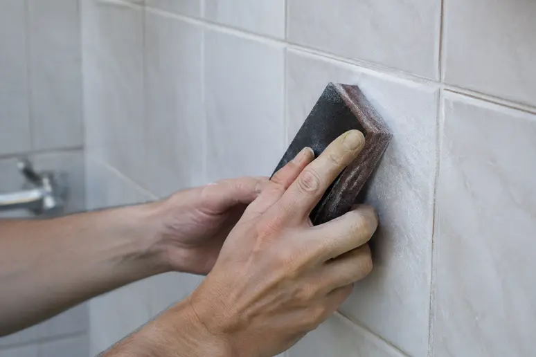 Ponçage d'un carrelage mural avec un bloc abrasif pour préparer la pose d'une peinture résine carrelage