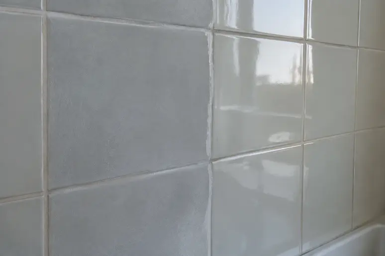 Carrelage mural partiellement poncé montrant une surface mate et uniforme prête pour la résine