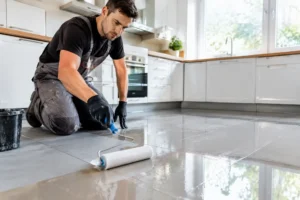 Application minutieuse de peinture resine carrelage sur le sol d'une cuisine en rénovation