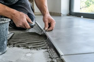 Pose d'un profilé pour carrelage mesurant l'épaisseur exacte avec la colle sur un chantier