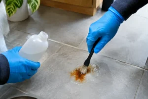 Gant de protection appliquant un traitement pour savoir comment retirer de la rouille sur du carrelage ancien.