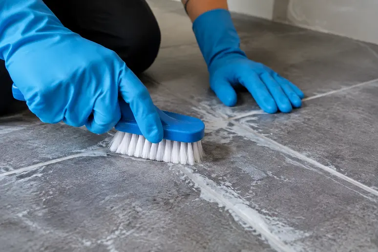 Nettoyage minutieux d'un voile de laitance sur le carrelage avec une brosse en nylon