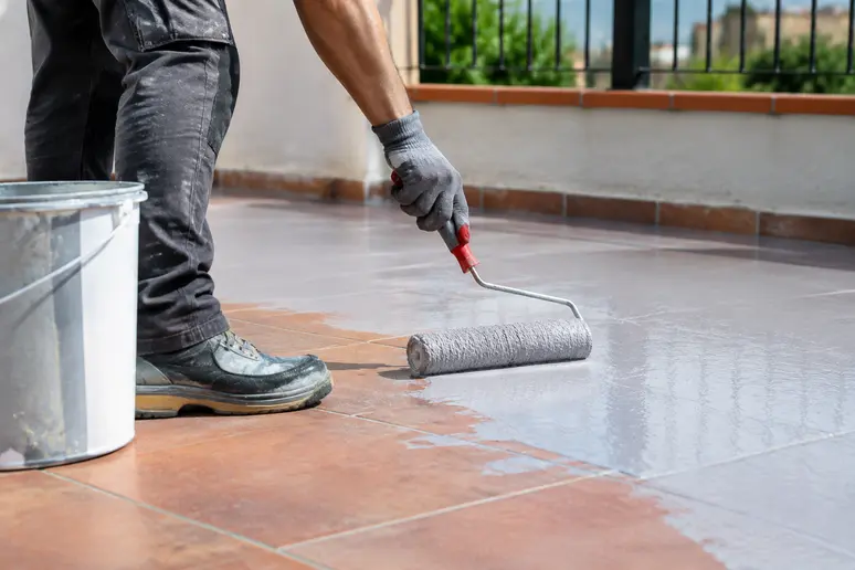 Application d'un primaire d'accrochage au rouleau sur un carrelage extérieur avant peinture