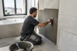 Artisan posant du carrelage mural lors de la pose carrelage salle de bain dans un logement.