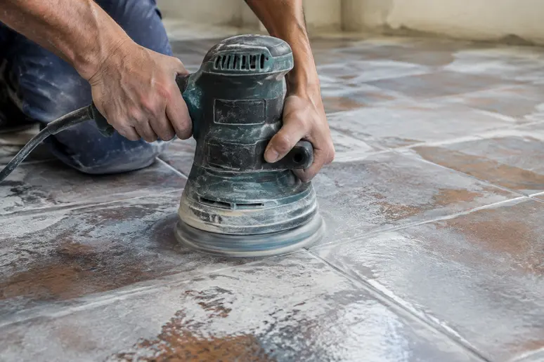 Ponçage d'un carrelage existant pour améliorer l'adhérence avant la pose d'un ragréage sur carrelage.
