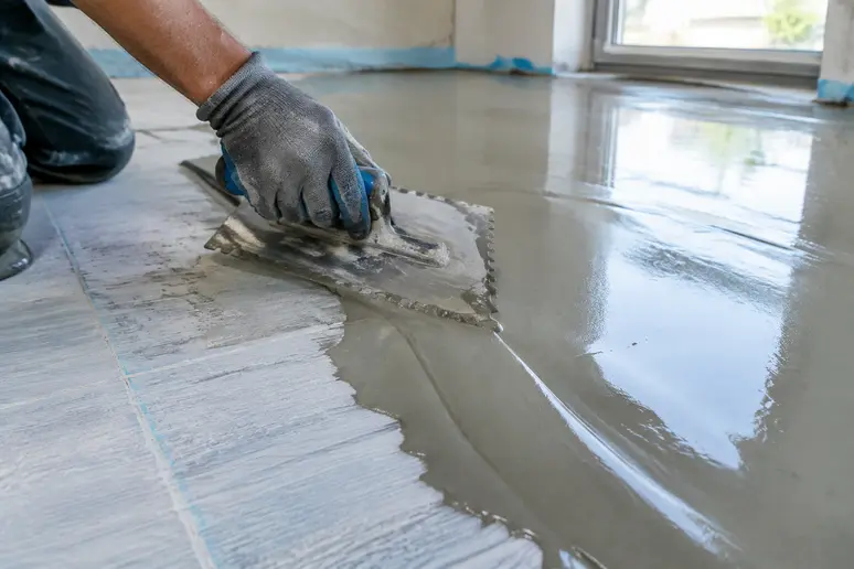 Application au platoir d'une couche de ragréage sur carrelage selon l'épaisseur recommandée.