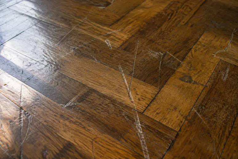 Plusieurs rayures profondes et marques d'usure visibles sur des lames de parquet ancien