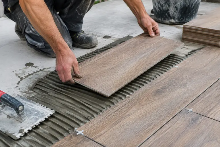 Pose collée d'un carrelage extérieur imitation bois sur une dalle en béton préparée